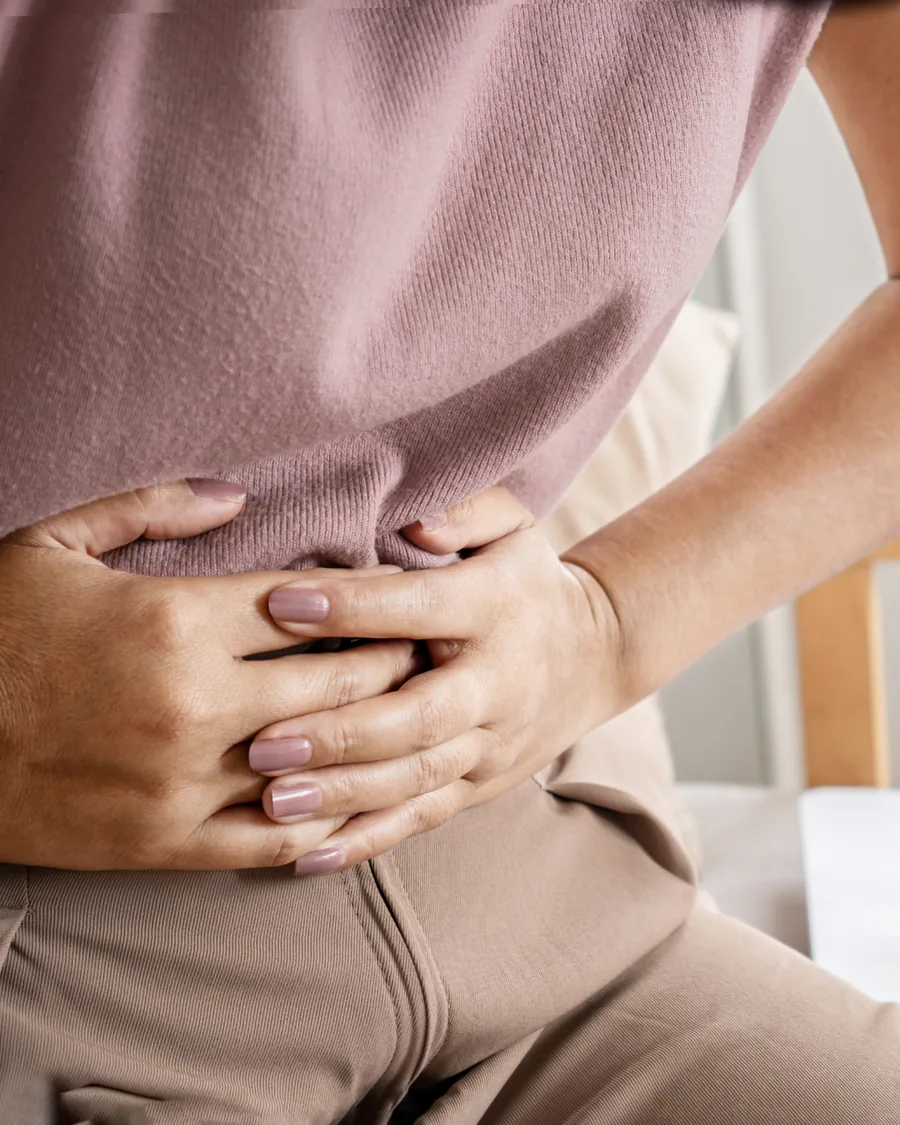 A woman holding her midsection with both hands.