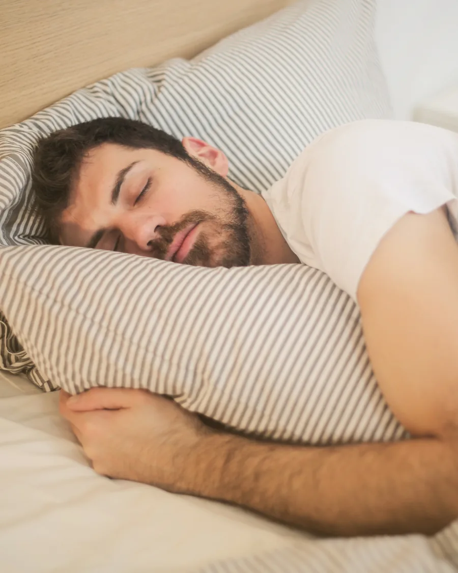A man asleep in bed, resting on a pillow.
