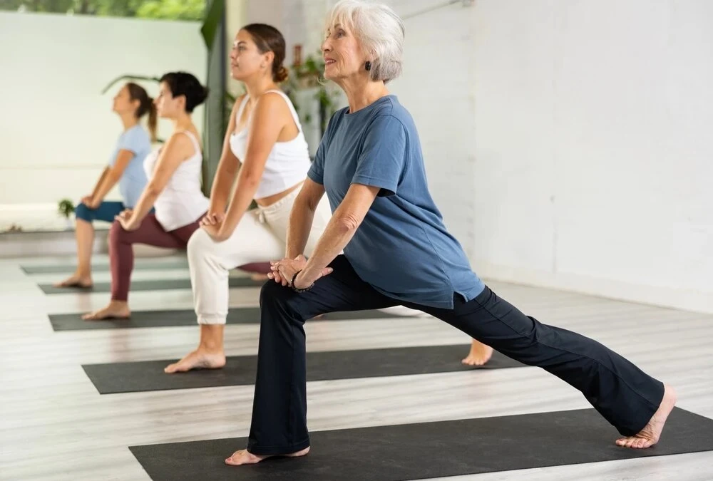 An adult over 50 practicing yoga outdoors in natural light, representing the clinical health benefits of yoga for cardiovascular health, stress reduction, and balance.