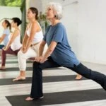 An adult over 50 practicing yoga outdoors in natural light, representing the clinical health benefits of yoga for cardiovascular health, stress reduction, and balance.